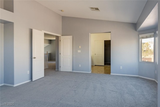 unfurnished bedroom with visible vents, high vaulted ceiling, baseboards, and carpet floors