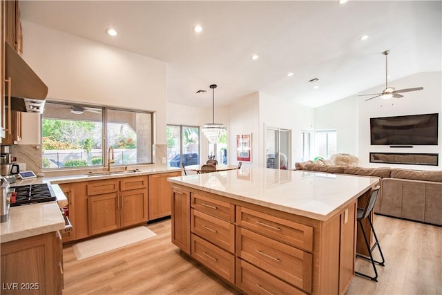 kitchen featuring a healthy amount of sunlight, range hood, vaulted ceiling, and a sink