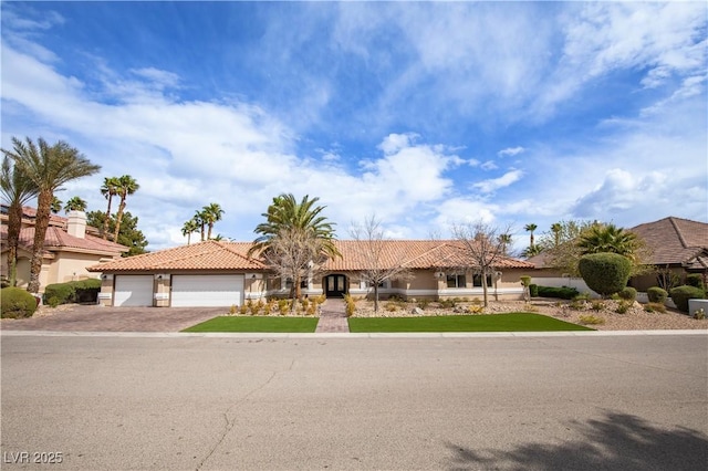 view of front facade with a garage, a tile roof, driveway, and stucco siding