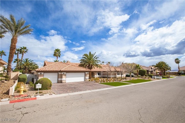 view of front of house with a tiled roof, decorative driveway, an attached garage, and stucco siding