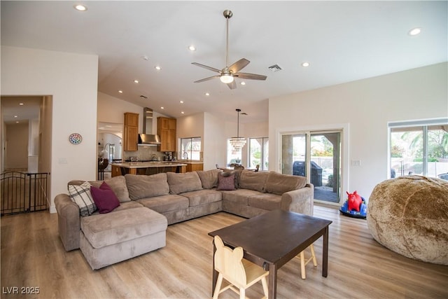 living area with visible vents, ceiling fan, light wood-type flooring, high vaulted ceiling, and recessed lighting