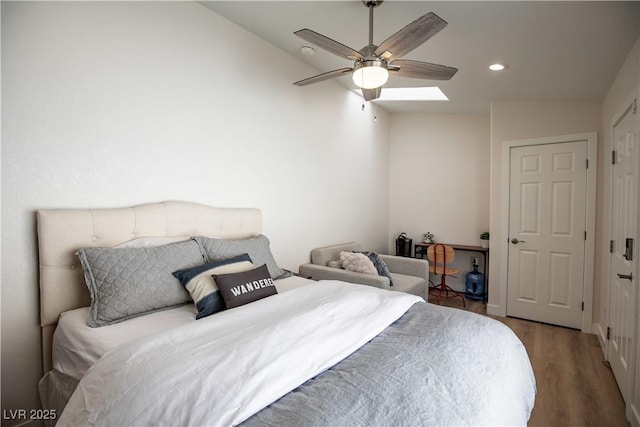 bedroom featuring ceiling fan, vaulted ceiling with skylight, wood finished floors, and recessed lighting