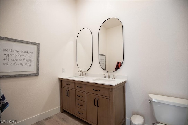 full bathroom featuring double vanity, wood finished floors, a sink, and toilet