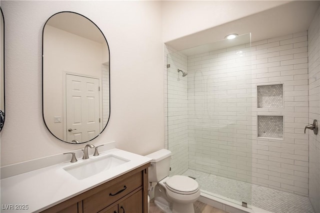 bathroom featuring toilet, a tile shower, and vanity