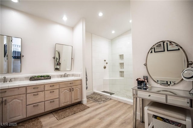 full bathroom with lofted ceiling, a sink, wood finished floors, a shower stall, and double vanity