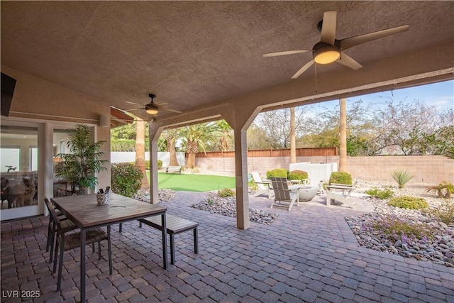 view of patio with fence private yard, ceiling fan, and a fire pit