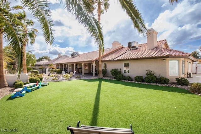 rear view of property with stucco siding, a lawn, a patio area, fence, and a tiled roof