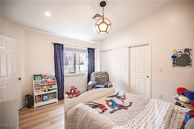 bedroom featuring lofted ceiling, light wood finished floors, visible vents, and a closet