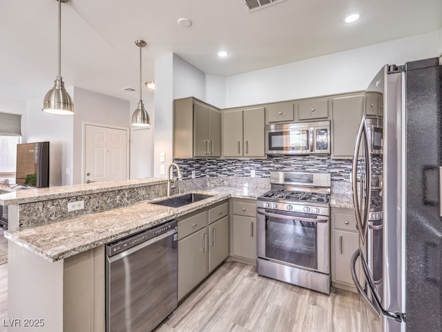 kitchen featuring gray cabinets, a sink, backsplash, stainless steel appliances, and a peninsula