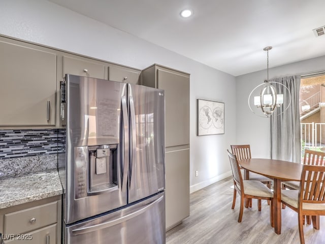 kitchen with gray cabinets, stainless steel refrigerator with ice dispenser, light wood-style floors, decorative backsplash, and a chandelier