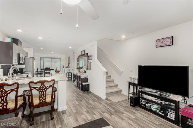 living room featuring stairs, baseboards, light wood-style flooring, and recessed lighting