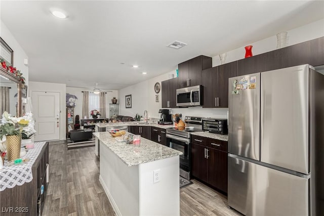 kitchen with visible vents, a kitchen island, stainless steel appliances, dark brown cabinets, and light wood-type flooring