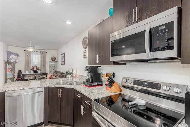 kitchen featuring dark brown cabinetry, ceiling fan, a peninsula, stainless steel appliances, and a sink