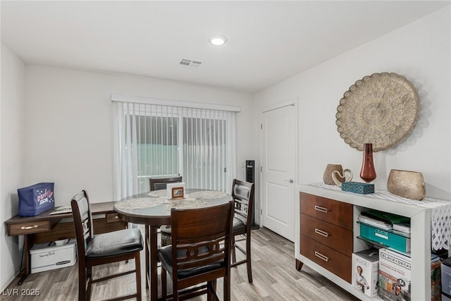 dining area with light wood finished floors, visible vents, and baseboards