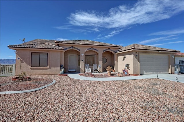 mediterranean / spanish home featuring driveway, a garage, a tile roof, fence, and stucco siding