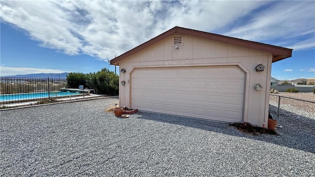 detached garage featuring fence and a fenced in pool