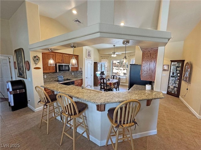 kitchen featuring stainless steel microwave, visible vents, light tile patterned flooring, high vaulted ceiling, and range