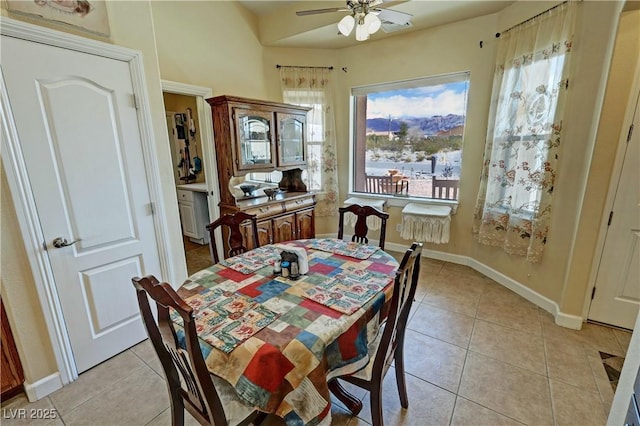 dining space featuring light tile patterned floors, ceiling fan, baseboards, and a mountain view