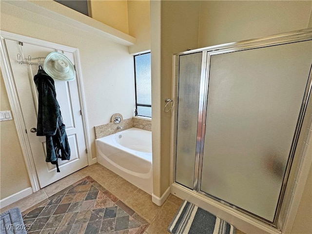 bathroom featuring a stall shower, baseboards, and a bath