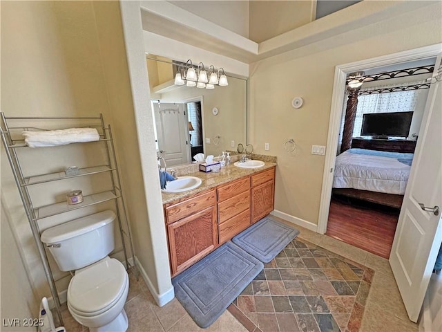 bathroom with double vanity, a sink, toilet, and connected bathroom