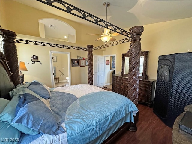 bedroom with visible vents, connected bathroom, a towering ceiling, ceiling fan, and wood finished floors