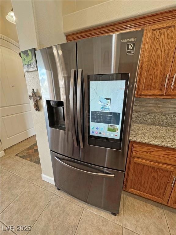 kitchen with decorative backsplash, brown cabinets, stainless steel fridge with ice dispenser, and light tile patterned floors