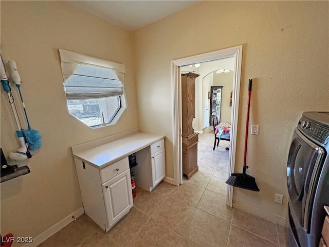 laundry area with arched walkways, light tile patterned floors, washer / clothes dryer, laundry area, and baseboards