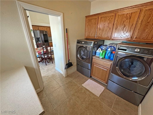 laundry area with light tile patterned floors, washing machine and dryer, cabinet space, and baseboards