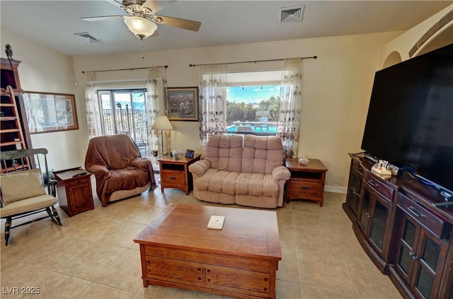 living area featuring light tile patterned floors, ceiling fan, visible vents, and baseboards