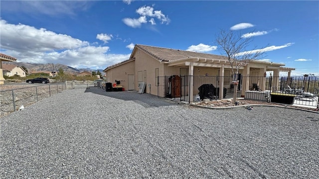 view of side of home featuring fence, a patio area, a mountain view, a pergola, and stucco siding