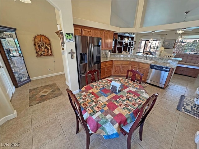 kitchen featuring appliances with stainless steel finishes, light tile patterned flooring, a sink, high vaulted ceiling, and a peninsula