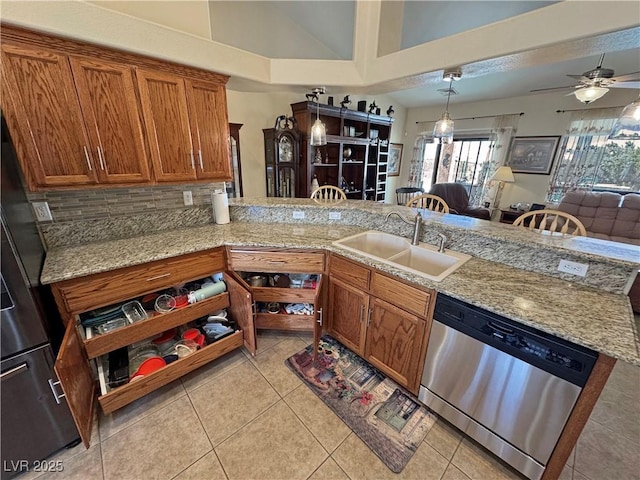 kitchen featuring light tile patterned floors, dishwasher, brown cabinets, a peninsula, and a sink