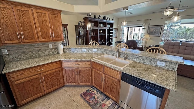 kitchen with stainless steel dishwasher, brown cabinetry, light tile patterned flooring, a sink, and a peninsula