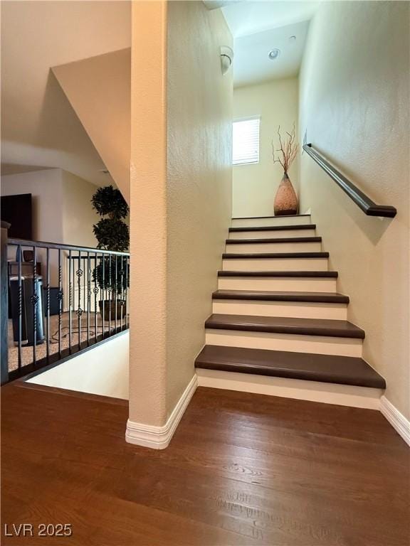 staircase featuring baseboards and wood finished floors