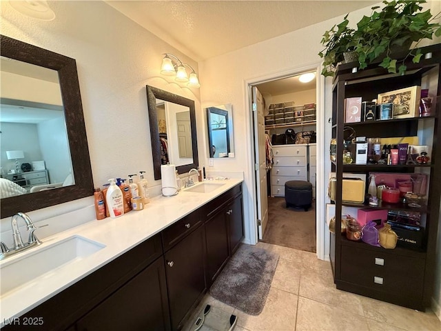 bathroom with double vanity, a spacious closet, a sink, and tile patterned floors