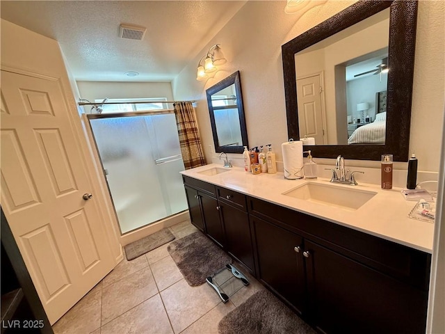 ensuite bathroom with a textured ceiling, a sink, visible vents, and a shower stall