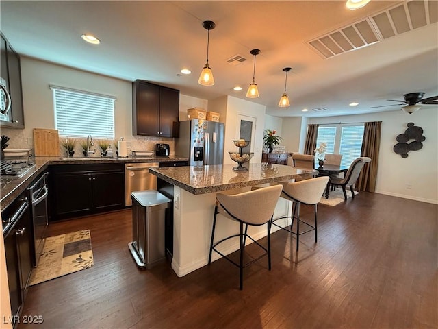 kitchen with visible vents, a breakfast bar area, a center island, stainless steel appliances, and a sink