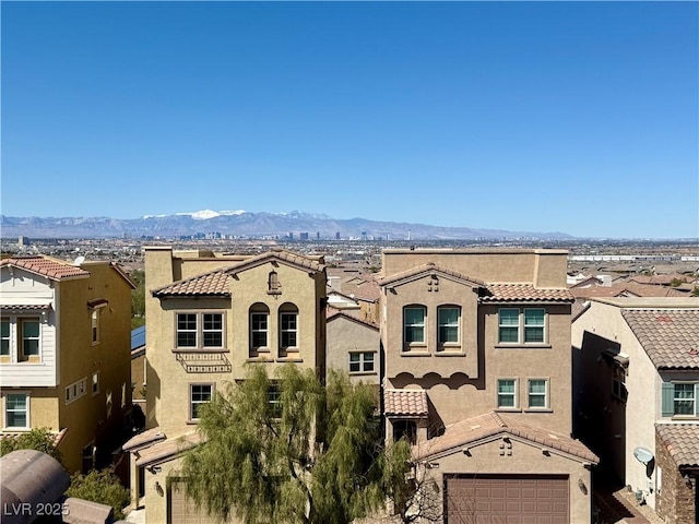 exterior space with a mountain view, a tiled roof, an attached garage, and stucco siding