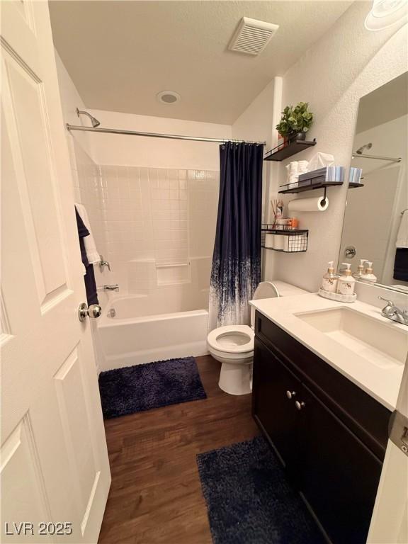 full bathroom with visible vents, toilet, wood finished floors, shower / bath combination with curtain, and vanity