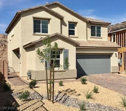 view of front of house with a tiled roof, stucco siding, driveway, and an attached garage