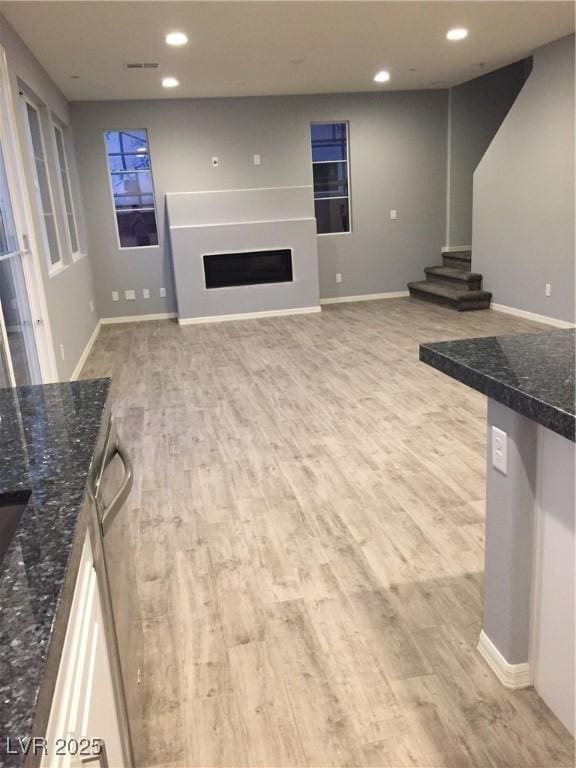 unfurnished living room featuring stairway, baseboards, light wood-style flooring, recessed lighting, and a fireplace