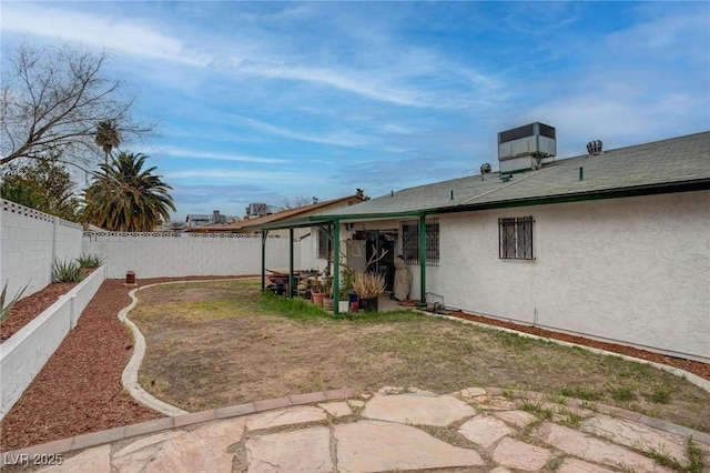 rear view of property featuring a fenced backyard, central AC, and stucco siding