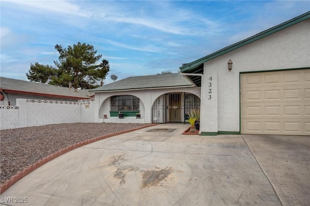 property entrance with driveway, an attached garage, fence, and stucco siding