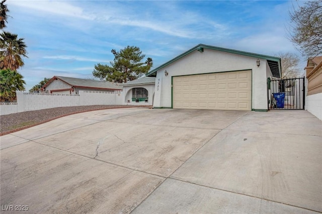 exterior space featuring fence, driveway, an attached garage, and stucco siding