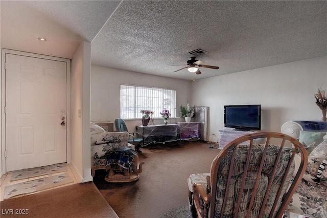 carpeted living room with ceiling fan, visible vents, and a textured ceiling