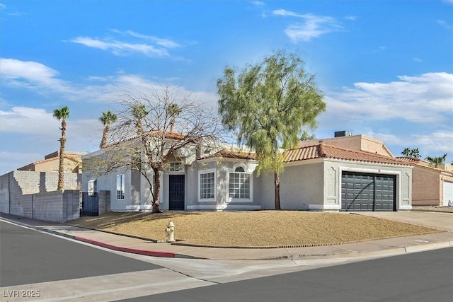 mediterranean / spanish-style house with a garage, a tile roof, driveway, and stucco siding