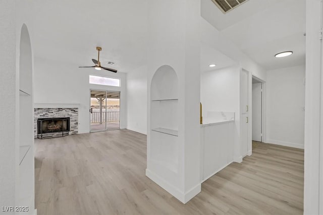 interior space with light wood-type flooring, baseboards, visible vents, and arched walkways