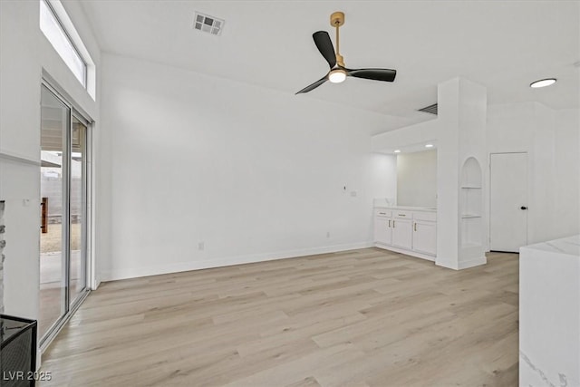 spare room featuring light wood finished floors, baseboards, visible vents, and a ceiling fan