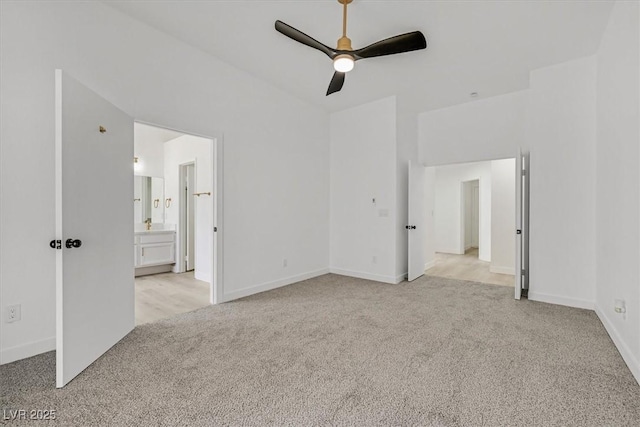 unfurnished bedroom featuring light carpet, ceiling fan, baseboards, and ensuite bathroom