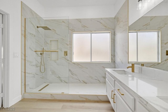 full bathroom featuring a marble finish shower, wood finished floors, and vanity